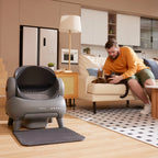 Neakasa automatic self-cleaning litter box in a modern living room while cat owner relaxes with his Bengal cat.
